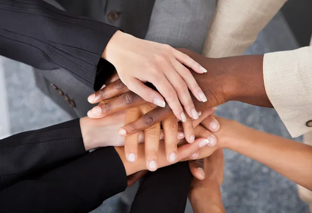 A group of business people putting their hands together.